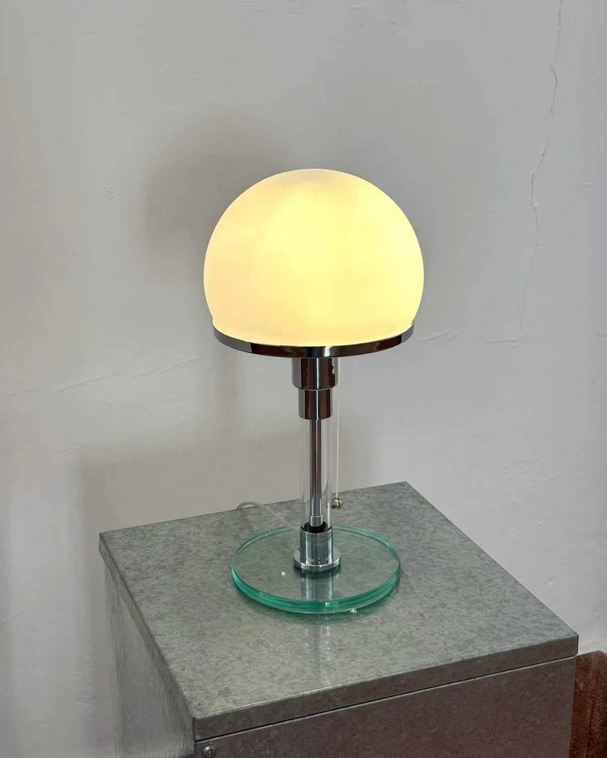 Bauhaus inspired table lamp with rounded dome shade and polished chrome stem for room decor.