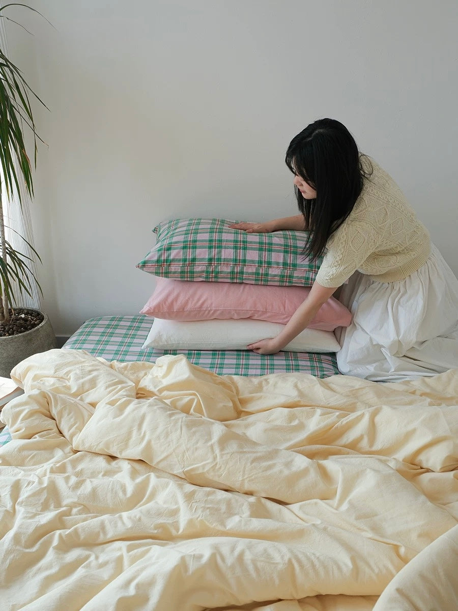 Woman arranging pillows on a bed with a neutral color scheme