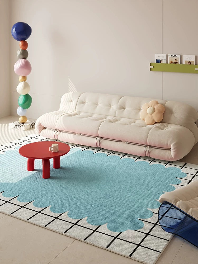 Modern living room with a blue rug, white sofa, and colorful decor elements.